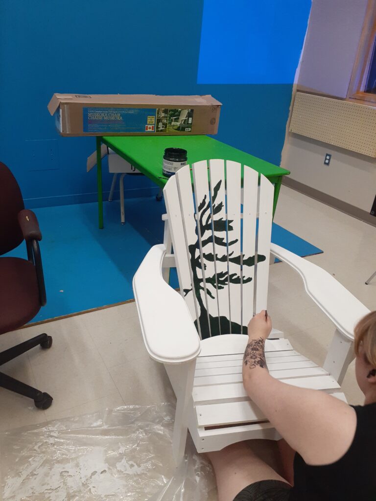 a white painted Muskoka Chair with a green tree on it